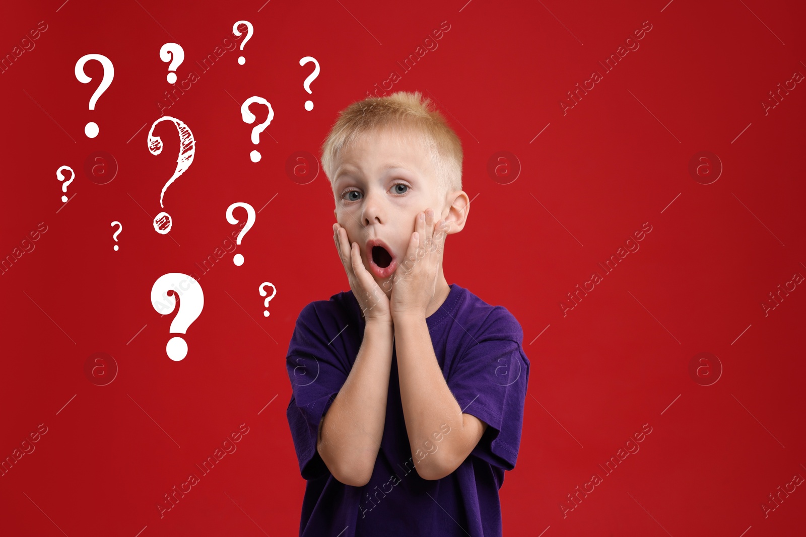 Image of Surprised boy on red background. White question marks near child