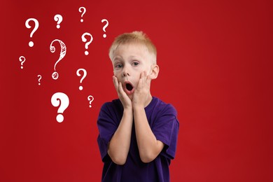 Image of Surprised boy on red background. White question marks near child