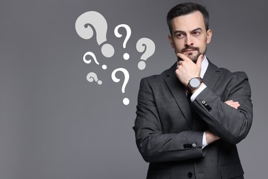 Image of Thoughtful businessman looking at question marks on grey background