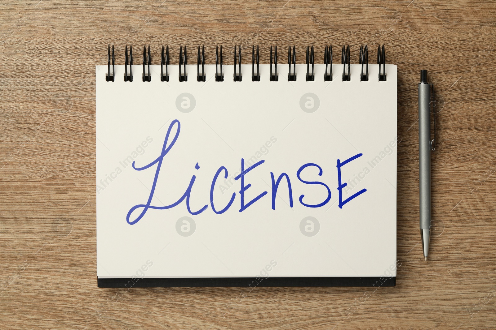 Image of License word written in notebook and pen on wooden background, top view