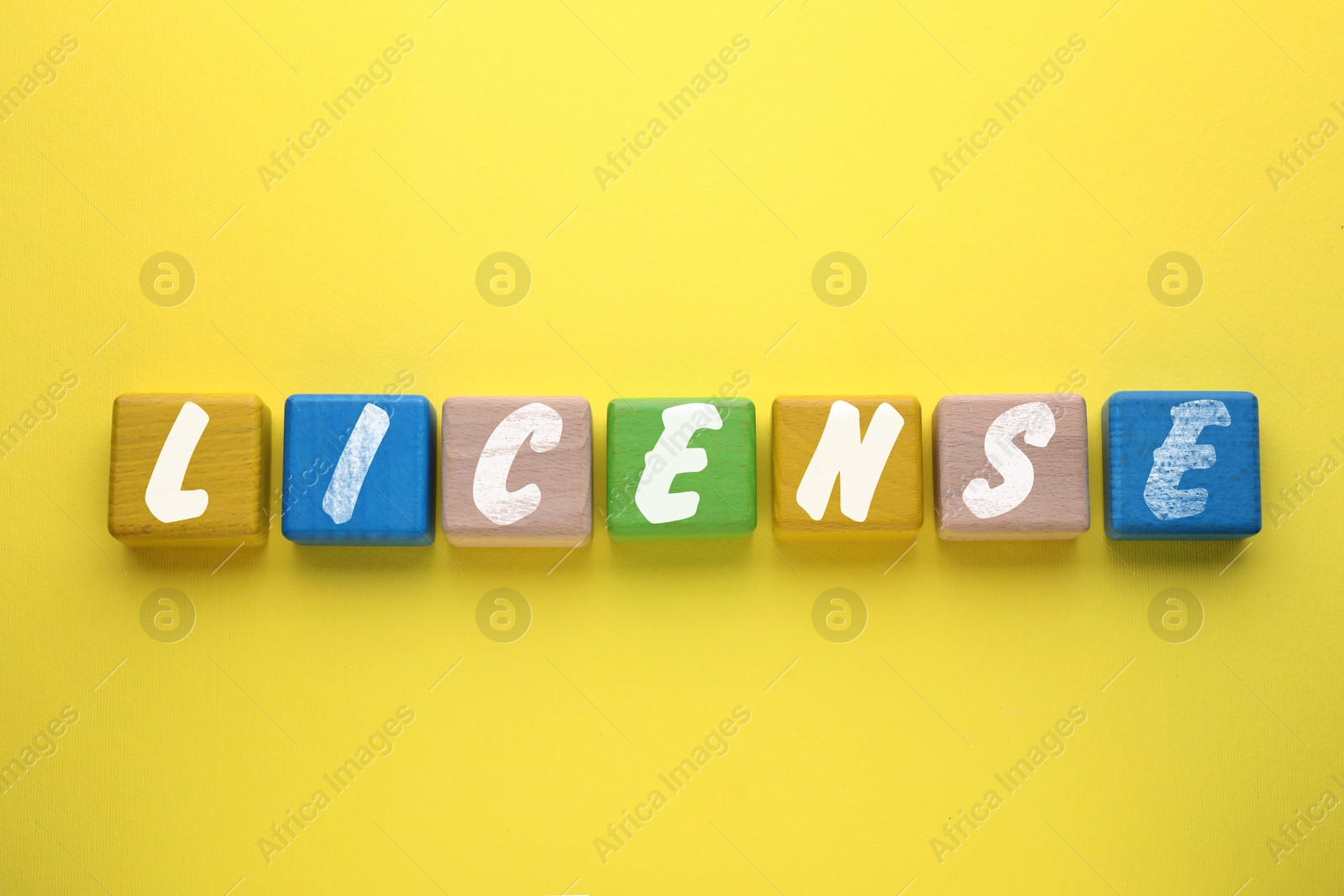 Image of License word made of colorful cubes with letters on yellow background, top view