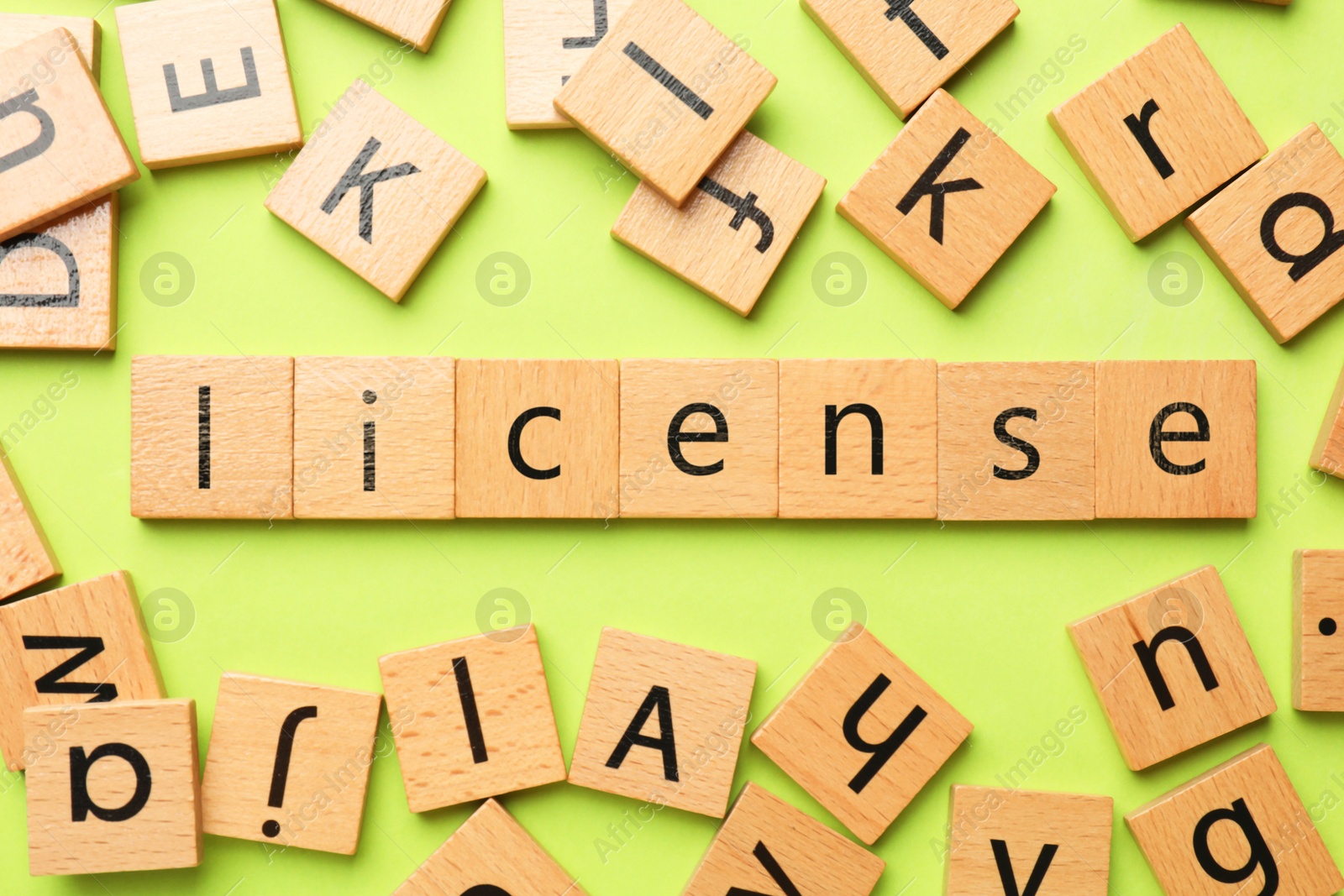 Image of License word made of wooden squares with letters on light green background, top view