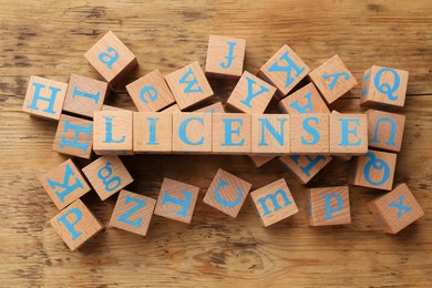 Image of License word made of cubes with letters on wooden background, top view