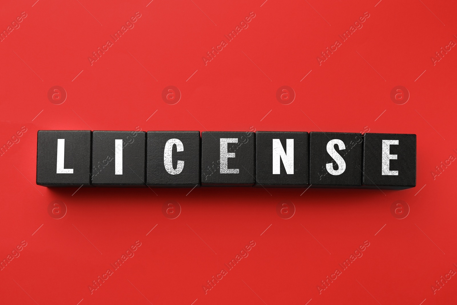 Image of License word made of black cubes with letters on red background, top view