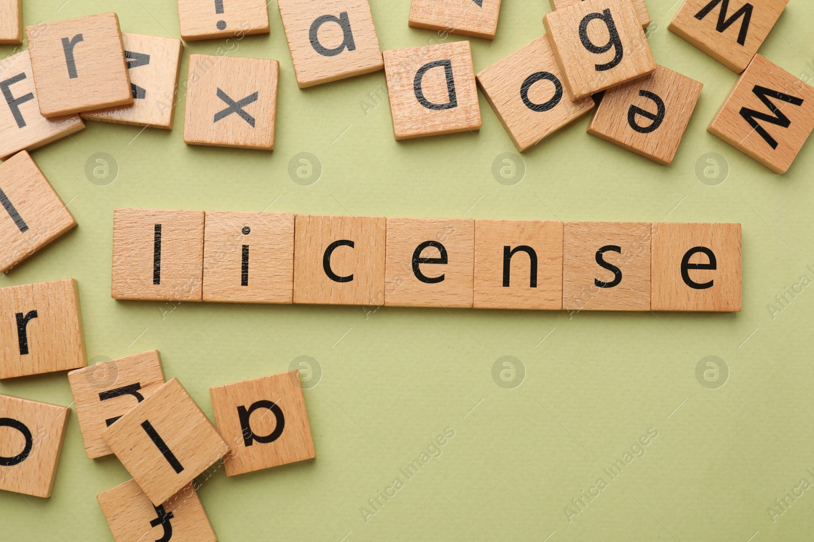 Image of License word made of wooden squares with letters on olive color background, top view