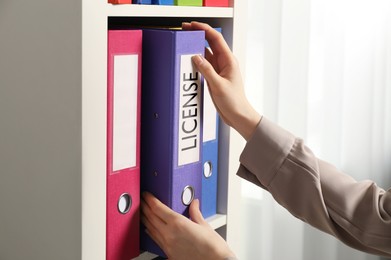 Image of Woman taking file folder with label License in office, closeup