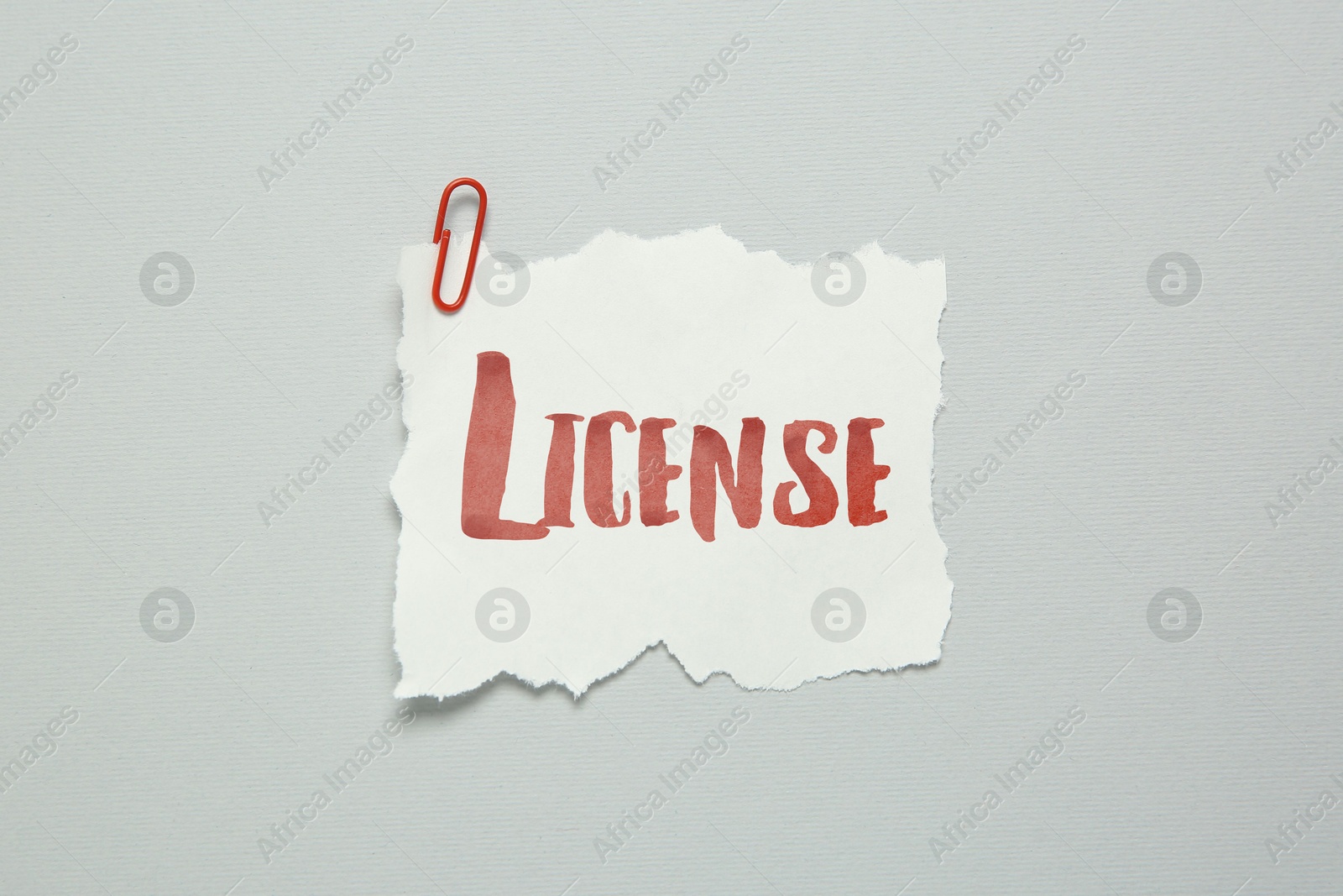 Image of Piece of paper with word License and paperclip on white background, top view