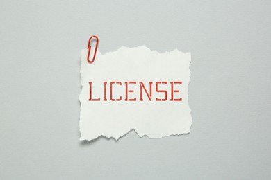 Image of Piece of paper with word License and paperclip on white background, top view