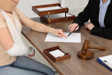 Photo of Injured woman having meeting with lawyer in office, closeup