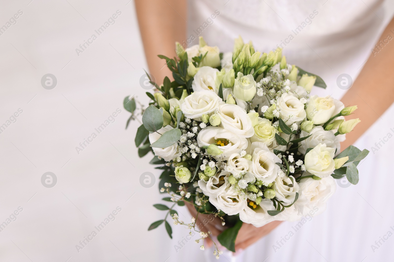 Photo of Bride with beautiful wedding bouquet on light background, closeup. Space for text