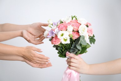 Photo of Bridesmaids giving beautiful wedding bouquet to bride on light background, closeup