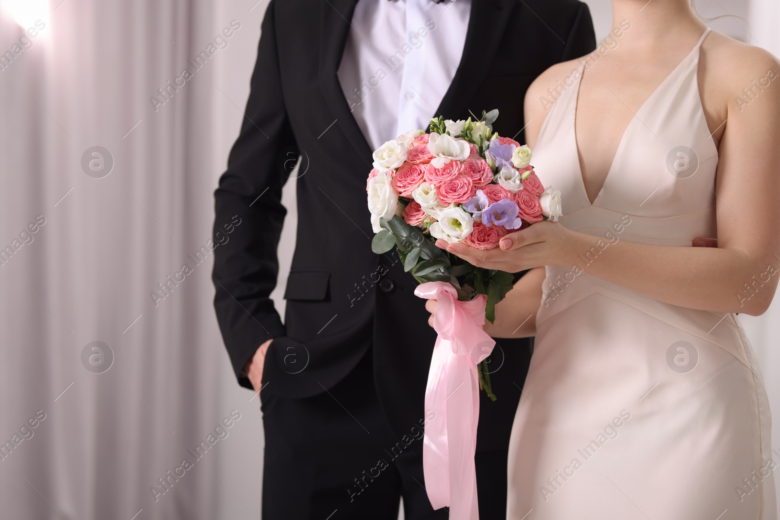 Photo of Bride with beautiful wedding bouquet and groom indoors, closeup. Space for text