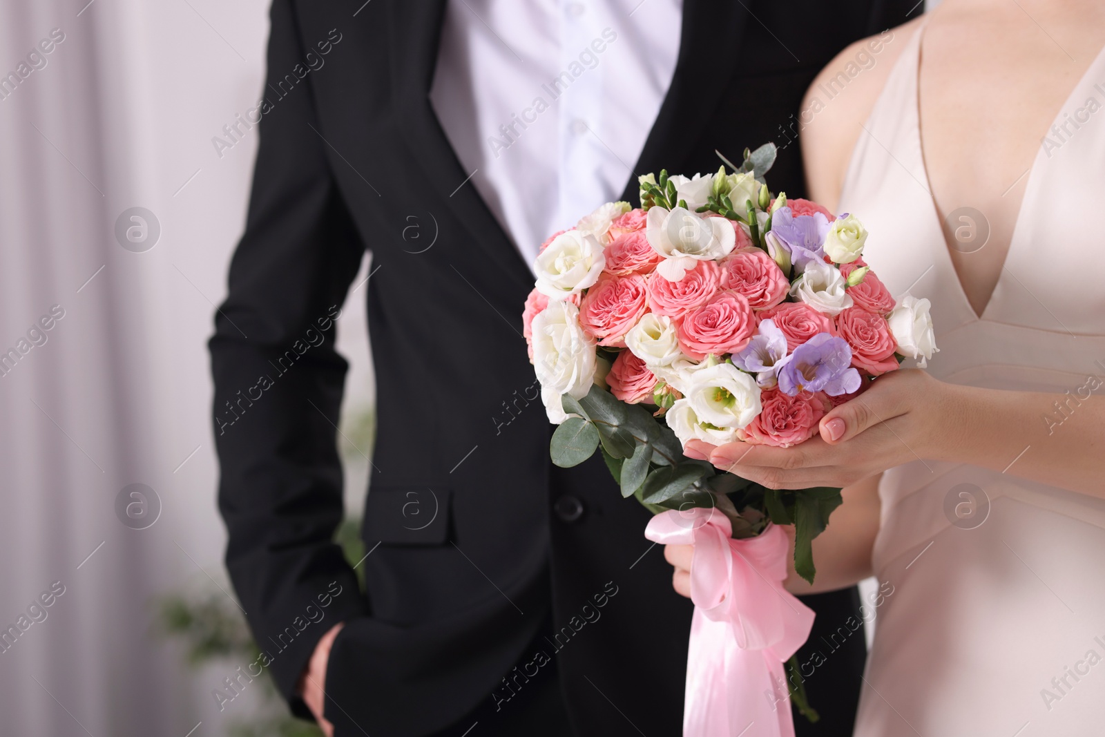 Photo of Bride with beautiful wedding bouquet and groom indoors, closeup