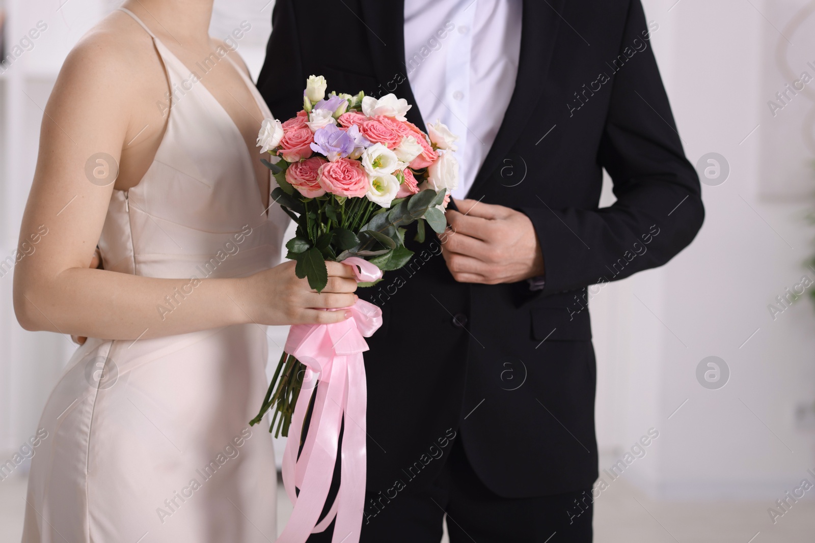 Photo of Bride with beautiful wedding bouquet and groom indoors, closeup