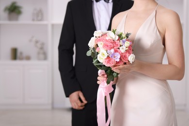 Photo of Bride with beautiful wedding bouquet and groom indoors, closeup. Space for text