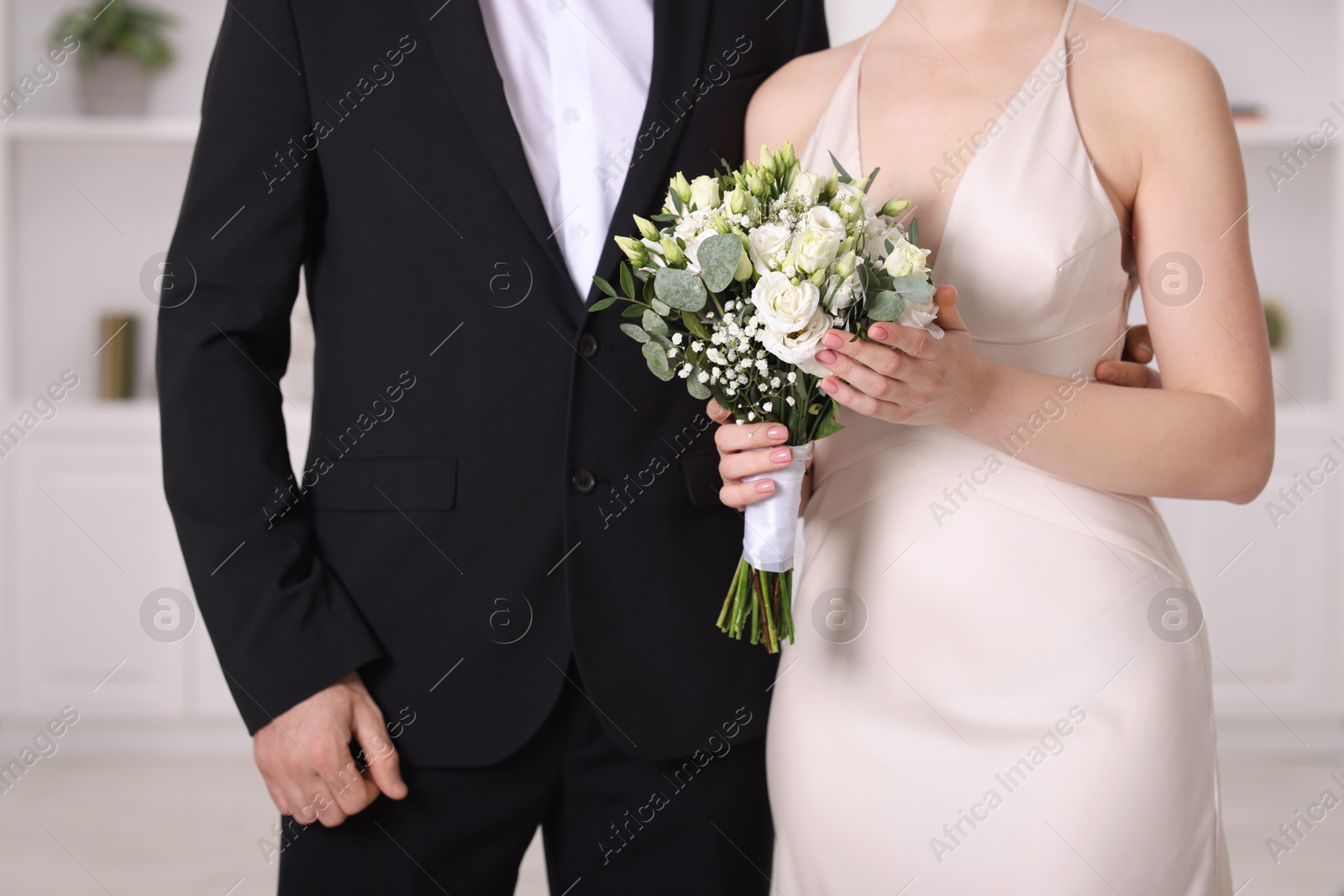 Photo of Bride with beautiful wedding bouquet and groom indoors, closeup