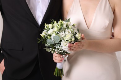 Photo of Bride with beautiful wedding bouquet and groom indoors, closeup