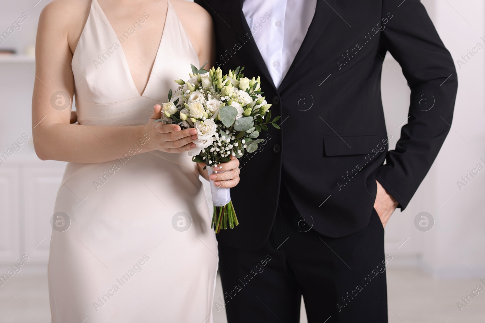 Photo of Bride with beautiful wedding bouquet and groom indoors, closeup