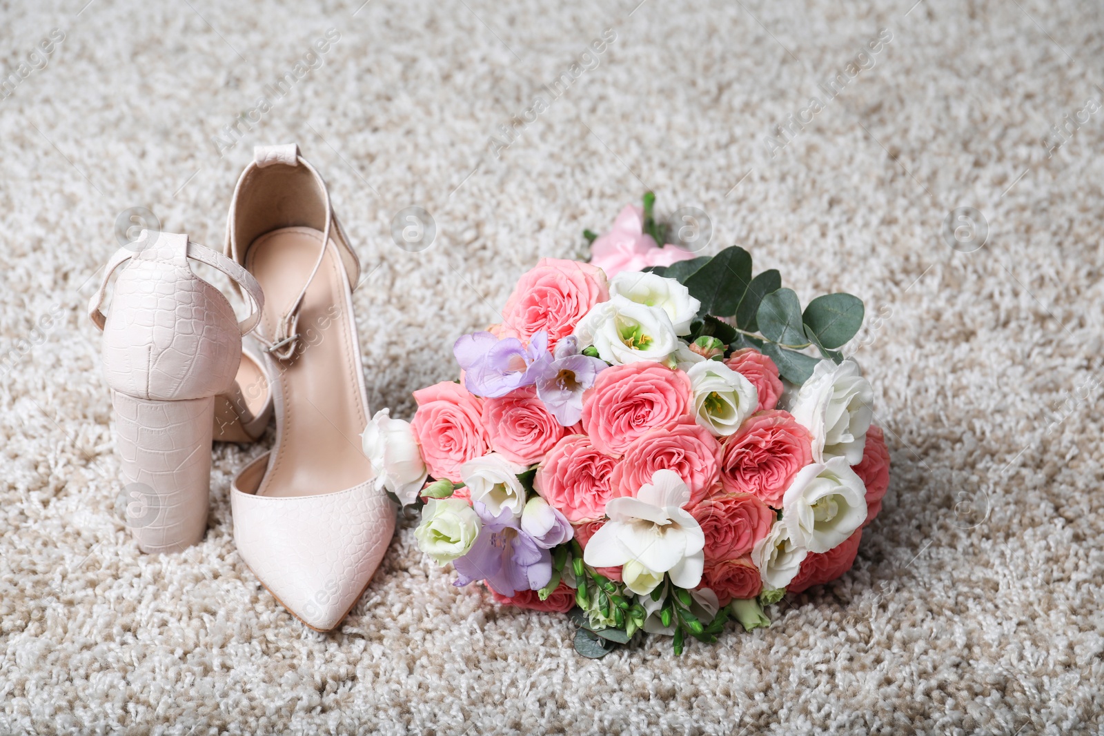 Photo of Wedding bouquet of beautiful flowers and bridal shoes on beige carpet