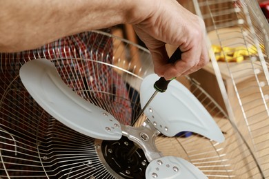 Photo of Relaxing hobby. Senior man repairing fan with screwdriver in workshop, closeup