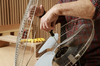 Photo of Relaxing hobby. Senior man repairing fan with screwdriver in workshop, closeup