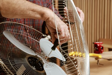 Photo of Relaxing hobby. Senior man repairing fan with screwdriver in workshop, closeup