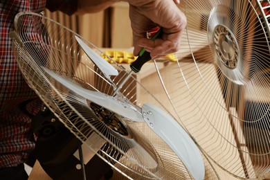 Photo of Relaxing hobby. Senior man repairing fan with screwdriver in workshop, closeup