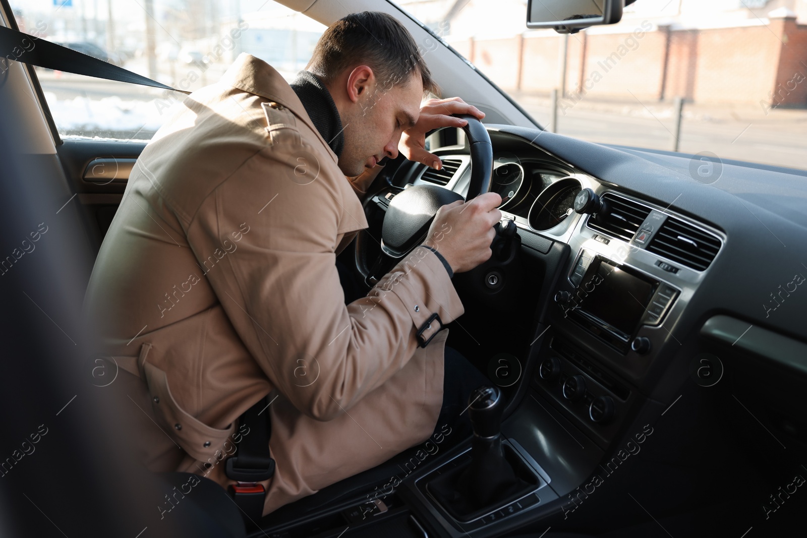 Photo of Tired driver sleeping on steering wheel in car