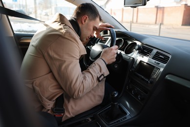 Photo of Tired driver sleeping on steering wheel in car