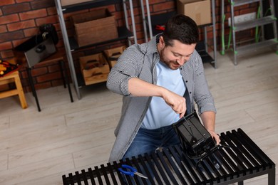 Photo of Relaxing hobby. Man repairing mechanical kitchen scale with screwdriver in workshop