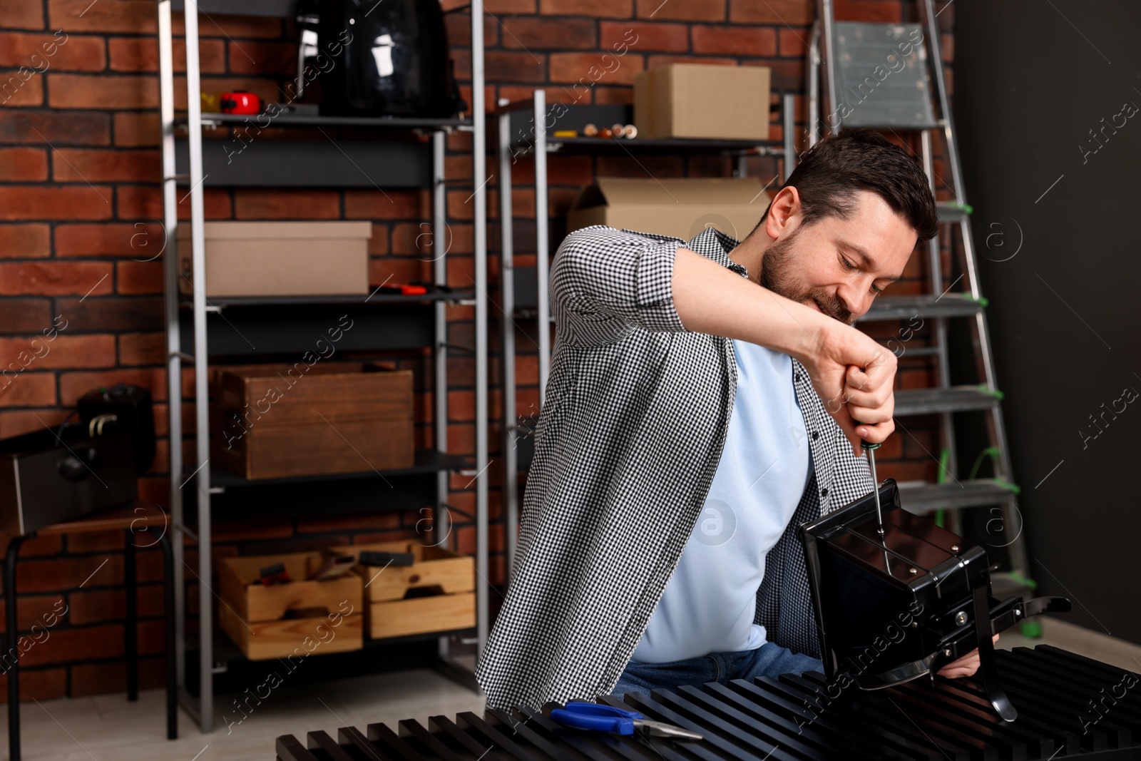 Photo of Relaxing hobby. Man repairing mechanical kitchen scale with screwdriver in workshop, space for text