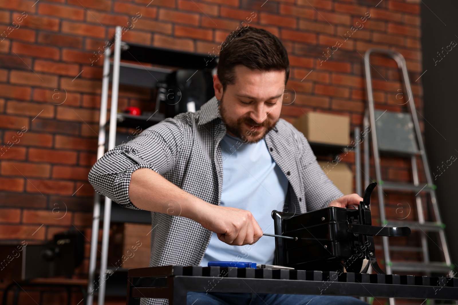 Photo of Relaxing hobby. Man repairing mechanical kitchen scale with screwdriver in workshop, low angle view