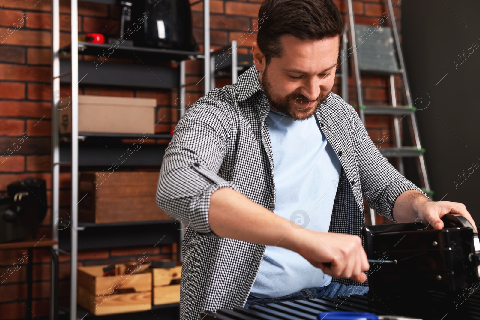 Photo of Relaxing hobby. Man repairing mechanical kitchen scale with screwdriver in workshop