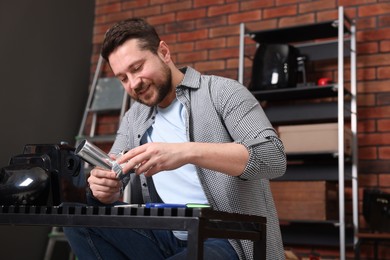 Photo of Relaxing hobby. Smiling man repairing electric meat grinder in workshop