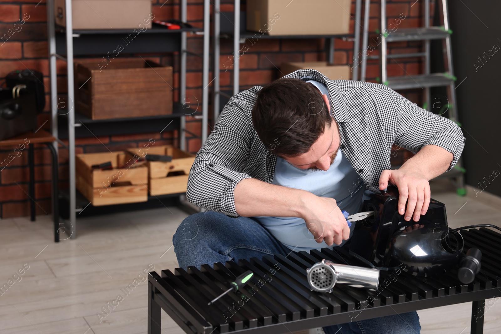 Photo of Relaxing hobby. Man repairing electric meat grinder in workshop, space for text