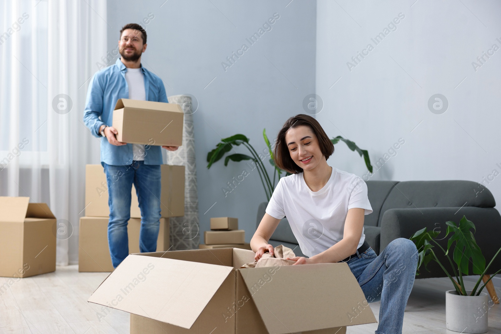 Photo of Moving day. Happy couple unpacking their belongings in new home, selective focus