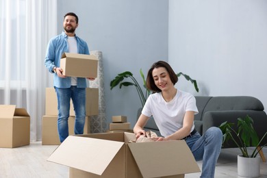 Photo of Moving day. Happy couple unpacking their belongings in new home, selective focus