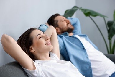 Photo of Moving day. Happy couple resting on couch in their new home, selective focus