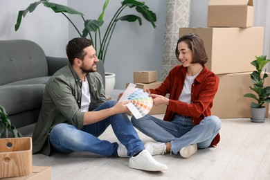 Photo of Moving day. Happy couple choosing paint color for their new home