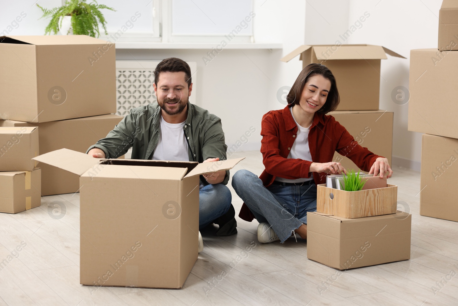 Photo of Moving day. Happy couple unpacking their belongings in new home