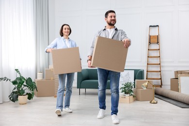 Photo of Moving day. Happy couple with cardboard boxes in their new home