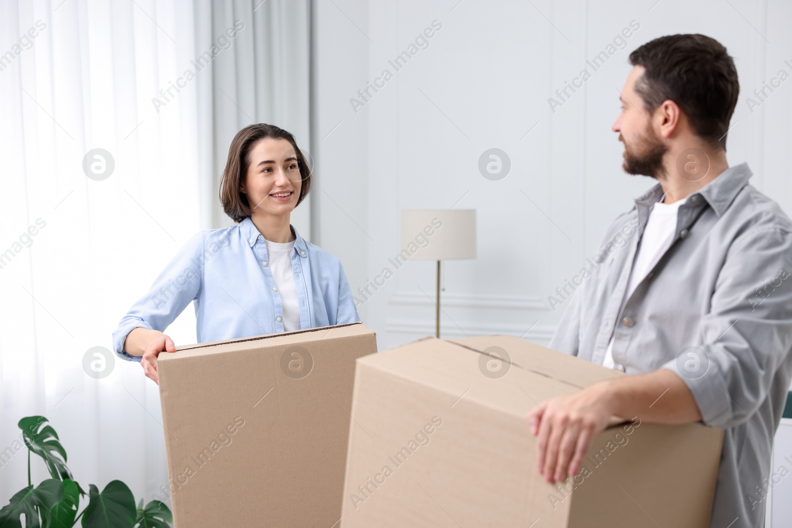 Photo of Moving day. Happy couple with cardboard boxes in their new home