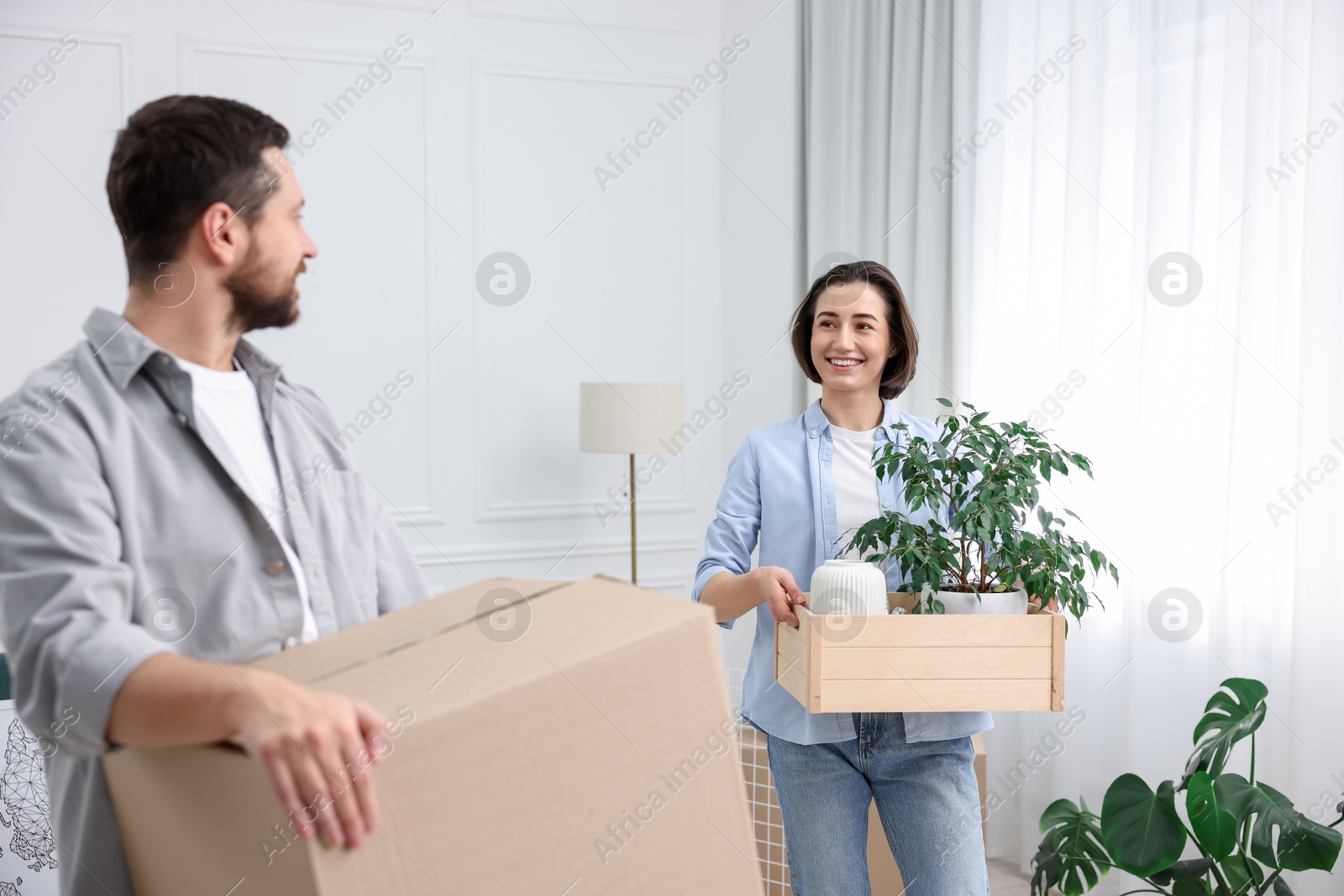 Photo of Moving day. Happy couple with their belongings in new home, selective focus