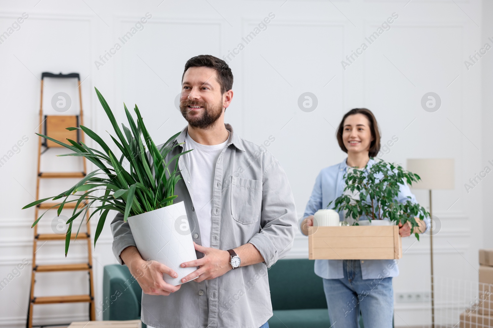 Photo of Moving day. Happy couple with their belongings in new home, selective focus