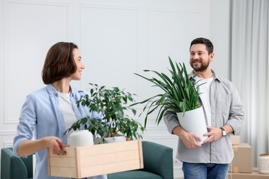 Photo of Moving day. Happy couple with their belongings in new home, selective focus