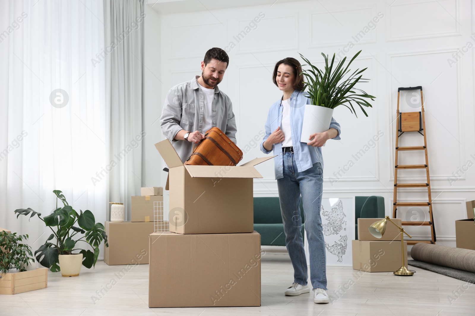 Photo of Moving day. Happy couple unpacking their belongings in new home