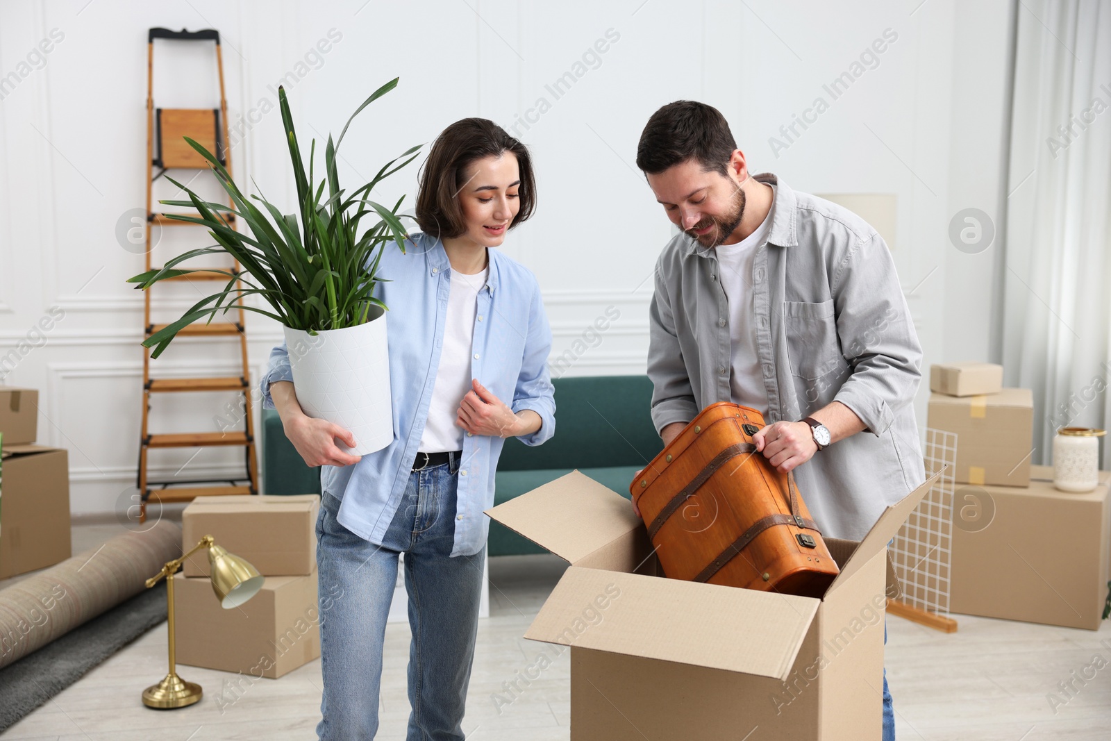 Photo of Moving day. Happy couple unpacking their belongings in new home