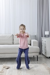 Photo of Little girl exercising at home. Morning routine