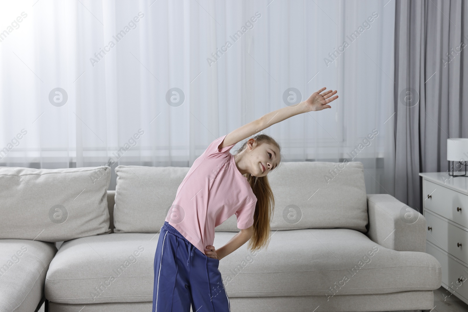 Photo of Little girl exercising at home. Morning routine