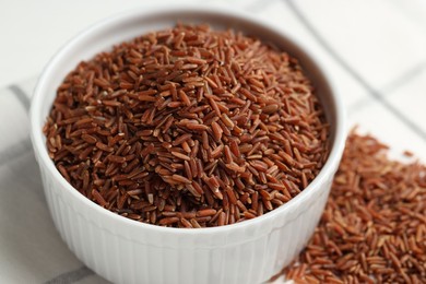 Photo of Raw brown rice in bowl on table, closeup